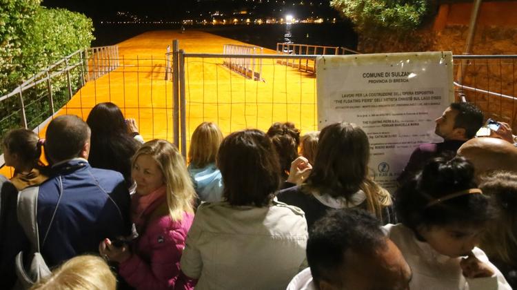 Le persone accalcate all’ingresso della passerella per rubare uno scorcio di «arte» sul lago FOTOLIVE