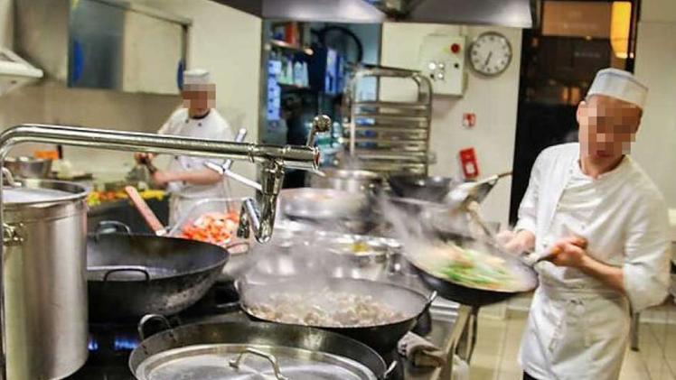 Due profughi   sorpresi a lavorare nelle cucine di un  ristorante