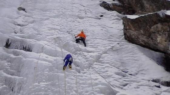 Due alpinisti impegnati nella scalata di una cascata di neve e ghiaccio