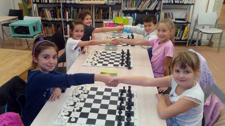 I bambini entusiasti si sfidano davanti alle scacchiere