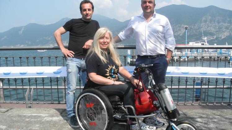 Massimo Brescianini con Riccarda Ambrosi accanto al «sollevatore»Riccarda con il suo «team» sullo sfondo dell’amato lago d’Iseo