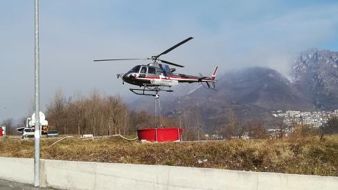Un elicottero impegnato a fare rifornimento di acqua per spegnere un incendio nei boschi di Lumezzane