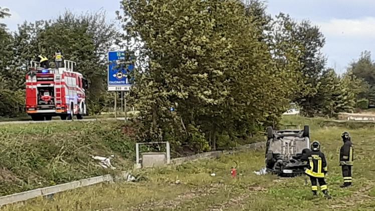Il tratto della strada provinciale che attraversa Montichiari in cui è avvenuto l’incidenteI Vigili del fuoco accanto all’automobile della donna ribaltata nel campo dopo essere uscita di strada