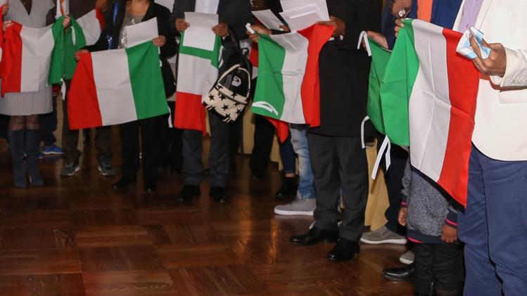 La bandiera italiana nelle mani di cittadini stranieri  durante il giuramento per ottenere la cittadinanza italiana