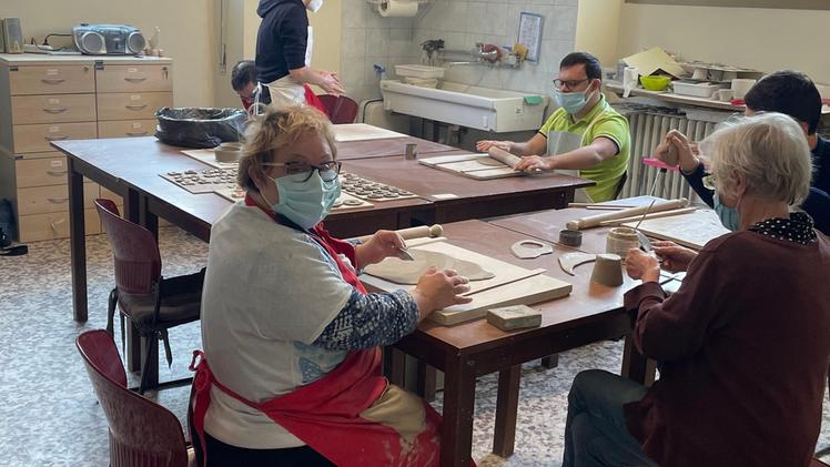 Volontari del laboratorio e utenti alle prese con la lavorazione dell’argillaAl lavoro nella bottega artigianale  di Nave