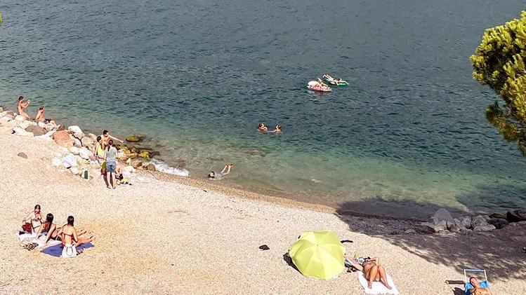 Turisti in spiaggia a Limone e c’è chi approfitta delle temperature sopra la media stagionale per farsi un bagno