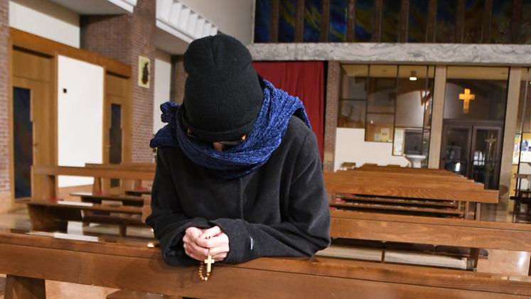 Una fedele in chiesa con cappotto, cappello e sciarpa